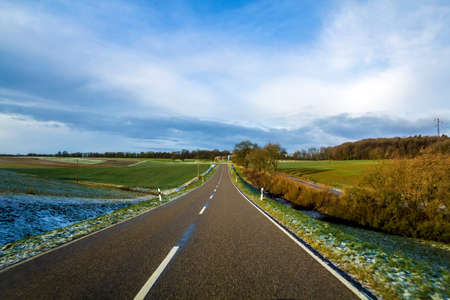 Empty black asphalt road between green fields.の写真素材