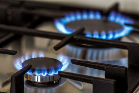 Natural gas burning on kitchen gas stove in the dark. Panel from steel with a gas ring burner on a black background, close-up shooting.の写真素材