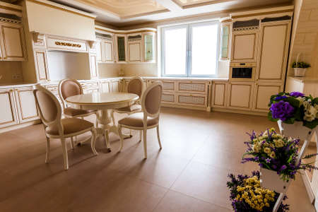 Luxury modern fitted kitchen interior. Kitchen in luxury home with beige cabinetry. Table and chairsの写真素材