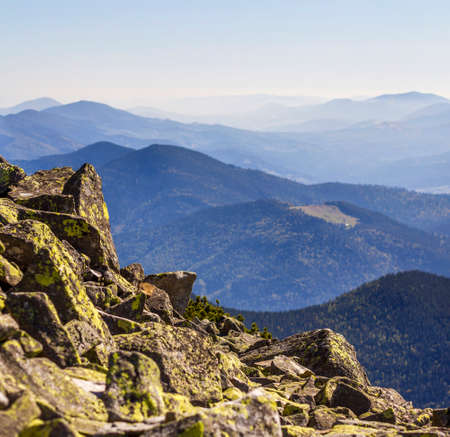 Stack of stones covered with moss on top of a mountain on mountains background. Concept of balance...