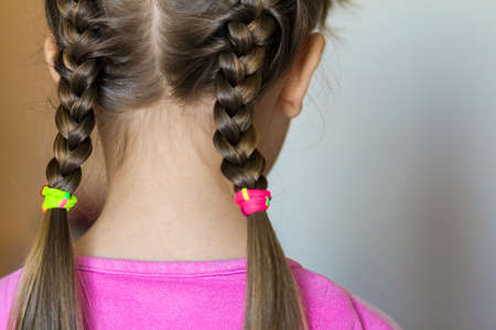 Close up rear- vew portrait of a cute little girl with funny pigtails on white background. Fashion and happy childhood.の写真素材