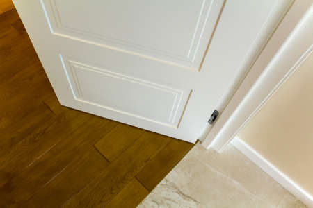 Modern house interior detail with wooden parquet floor and white door. Apartment after renovation close-up.の写真素材