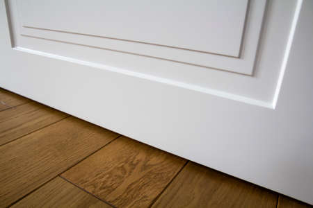 Modern house interior detail with wooden parquet floor and white door. Apartment after renovation close-up.の写真素材