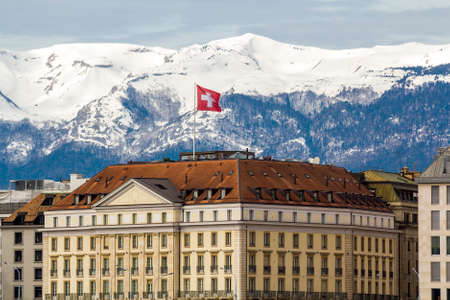Facades of historic buildings in the city center of Geneva, Switzerland on the Leman lake with snow covered Alps mountains peaks in sunny clear day.のeditorial素材
