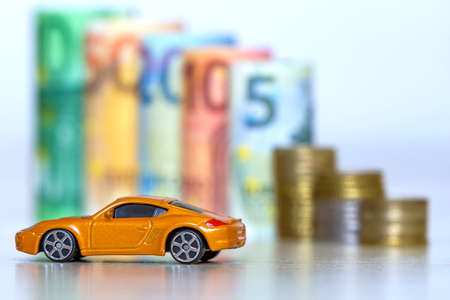 Blurred row of rolled hundred, fifty, twenty, ten and five new euro banknotes and pile of coins with...
