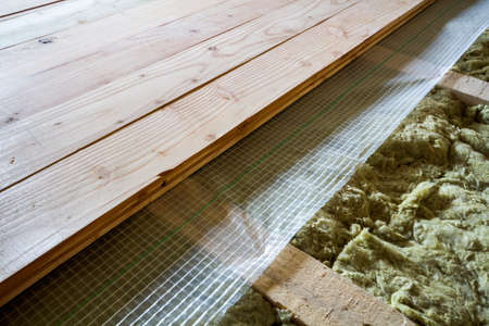 Installation of new floor of wooden natural planks and mineral wool insulation for isolation and keeping warmth. Construction, renovation, warm comfortable house concept.の写真素材