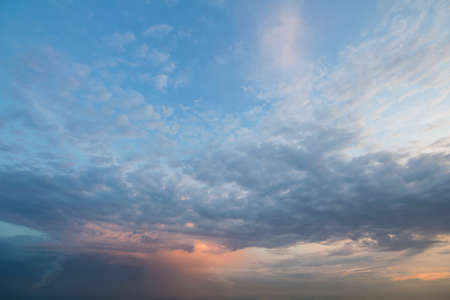 Panorama of sky at sunrise or sunset. Beautiful view of dark blue clouds lit by bright orange yellow...