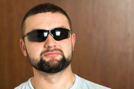 Portrait of handsome bearded black haired intelligent modern young man in glasses with short haircut and kind black eyes smiling on blurred background. Youth and confidence concept.の写真素材