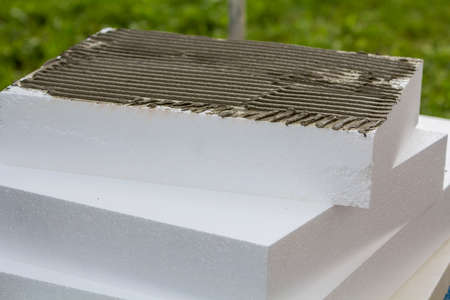 Close-up detail of stack of white rigid polyurethane foamboard sheets with applied glue for house insulation. Modern technology, renovation, energy saving, alternative for mineral wool concept.の写真素材