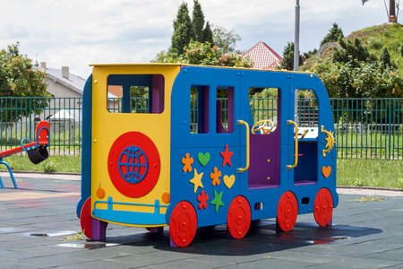 Beautiful new modern playground in kindergarten with soft rubber flooring, bright new multicolored big toy car and seesaw on bright sunny summer day. Perfect place for children activities outdoors.の写真素材