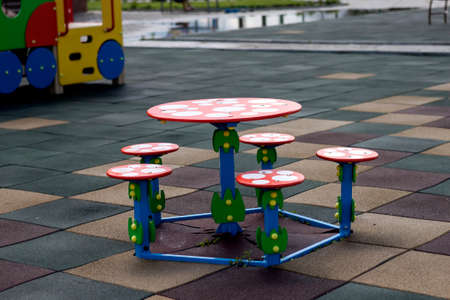 Close-up shot of bright colorful new round child small plastic table and five stools outdoors on...