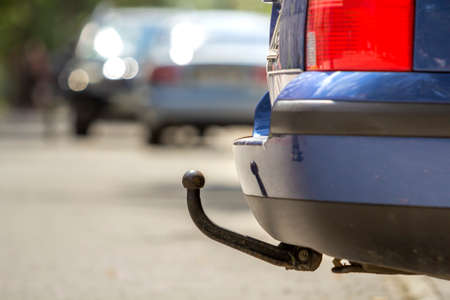 Close-up view detail of blue car parked on sunny street, red stop lights and hook for dragging trailer, tow hitch or tow bar on blurred copy space background. Transportation design and safety.の写真素材