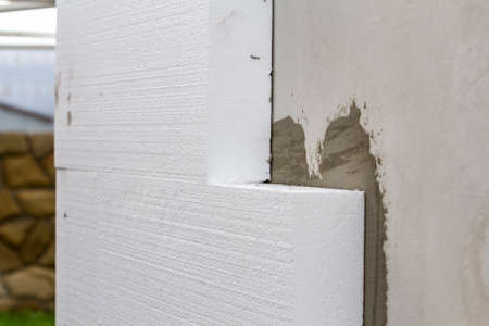 Close-up detail of plastered house wall with rigid styrofoam insulation. Modern technology, construction, renovation, energy saving, alternative for mineral wool, warm comfortable house concept.の写真素材