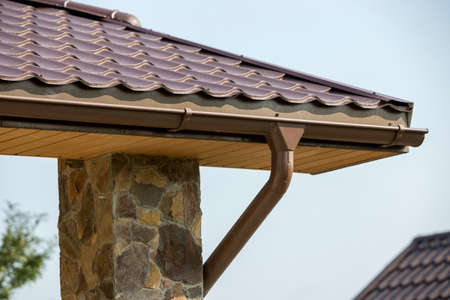 Detail of new modern house cottage corner with stucco walls decorated with natural stones, brown...