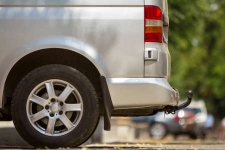 Close-up side view detail of silver passenger medium size luxury minibus van with tow-bar parked on...