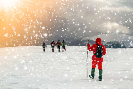 Tourists hikers in winter snow covered mountains and dramatic clouds in sky
