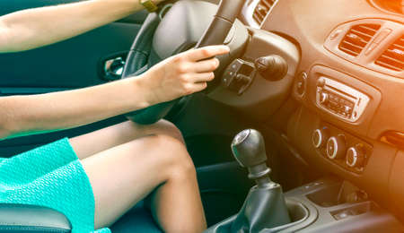 Beautiful tanned slim woman driver legs in a car. Girl in dress driving a car