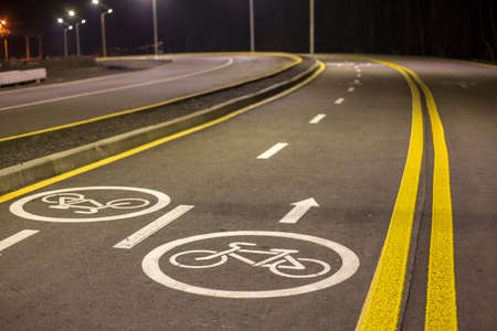 Bicycle Road Markings and Signs. Illuminated bicycle lane travel lane reserved for bicyclists with pavement markings with arrows that direct bicyclists in the direction of travel at night.の写真素材