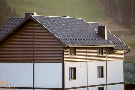 New nice white and brown two-storied cottage with shingle roof in ecological area on foggy wood and...