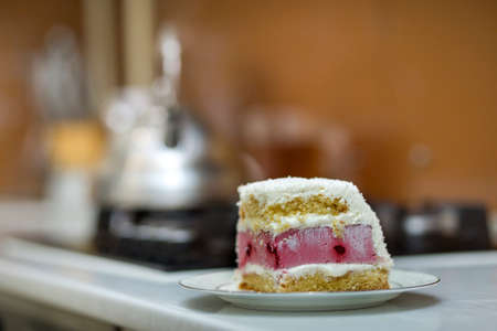 White plate with fresh delicious yummy homemade piece of fruit biscuit white and pink creamy cake on kitchen table on light blurred copy space background. Bakery and healthy food making concept.の写真素材