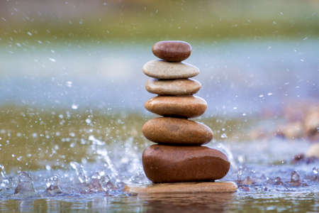 Close-up abstract image of wet rough natural brown uneven different sizes and forms stones balanced...
