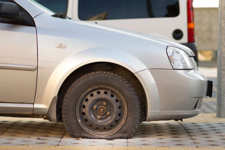 Flat tire of car on pavement. Side view outdoors of vehicle close up. Transportation problem, accident and insurance concept.の写真素材