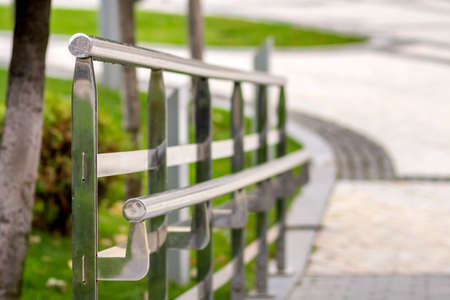 Metal fence construction made of shiny wet stainless pipes along road highway turn on copy space...