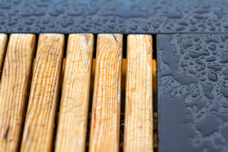 Wooden natural planks, polished boards, garden park bench with transparent big clear rain water...