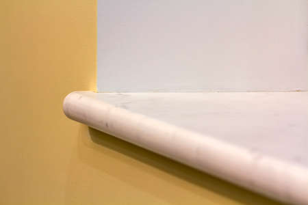 New white marble windowsill install on building yellow plastered wall. Construction, reconstruction...