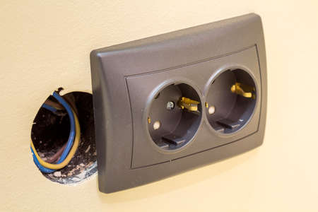 New gray power outlet socket with electric insulated colorful wires, plastic plug installation on...