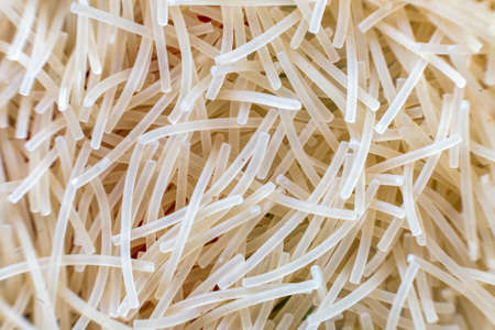 Close-up of raw dry uncooked pasta, abstract background. Italian traditional cuisine popular ingredient, nutrition, healthy tasty diet concept.の写真素材