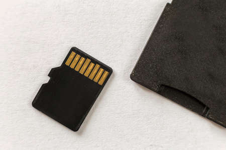 Close-up of micro SD memory card and SD adapter isolated on white copy space background. Modern...