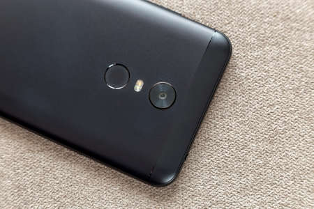 Back side of black cellphone isolated with security thumb fingerprint scanning device, camera and...