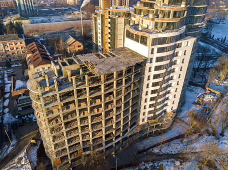 Aerial winter top view of modern developing city with tall apartment complex building under...