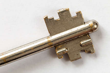 Close-up detail of old well-used steel key isolated on white copy space background. Safety and...