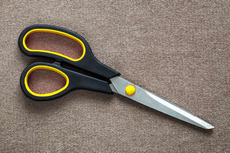 Close-up of sharp steel metal scissors isolated on light cloth copy space background. Household...