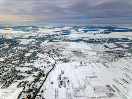Top view of empty snowy fields on winter morning on dramatic cloudy sky background. Aerial drone photography concept.の写真素材