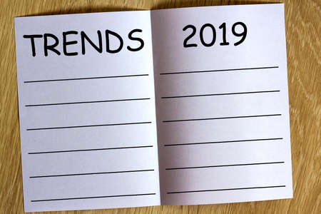 White sheen of paper on wooden background with text Trends 2019 on it.