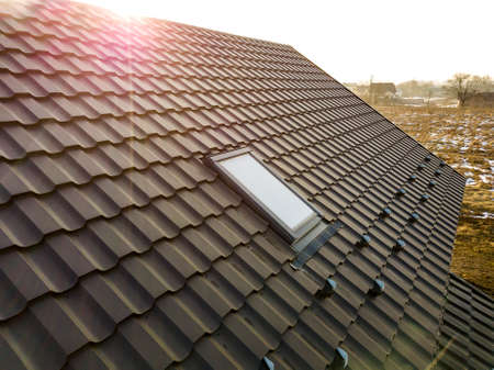 Close-up of new attic plastic window installed in shingled house roof. Professionally done building...