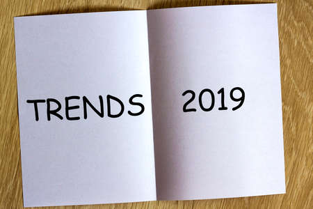 White sheen of paper on wooden background with text Trends 2019 on it.