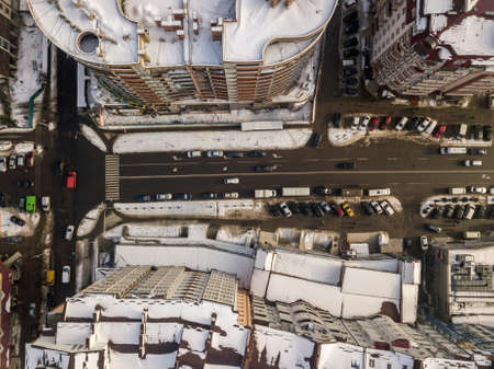 Aerial black and white winter top view of modern city with tall buildings, parked and moving cars along streets with road marking. Urban cityscape, view from above.の写真素材
