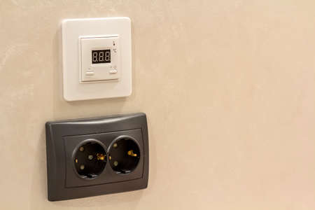 Double electric isolated socket and installed on light yellow plastered wall. Power supply and temperature regulation, energy saving, comfortable home concept.の写真素材
