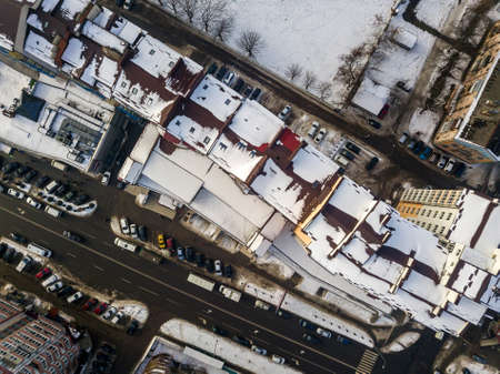 Aerial black and white winter top view of modern city with tall buildings, parked and moving cars along streets with road marking. Urban cityscape, view from above.の写真素材