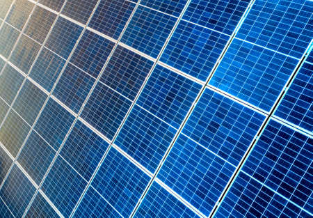 Close-up surface of lit by sun blue shiny solar photo voltaic panels. System producing renewable clean energy. Renewable ecological green energy production concept.の写真素材