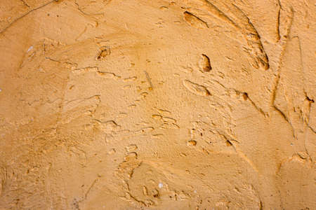 Close-up of colorful golden bronze plastered uneven stucco wall. Abstract texture, chaotic copy...
