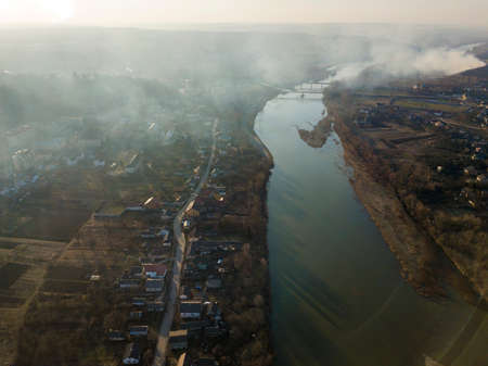 Aerial top view of river flowing through town. Rural landscape of residential house roofs, roads and...