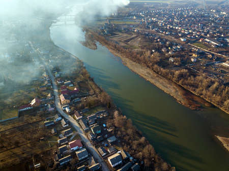 Aerial top view of river flowing through town. Rural landscape of residential house roofs, roads and...