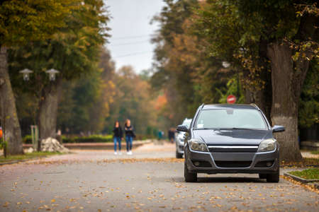 Gray shiny car parked in quiet area on asphalt road on blurred bokeh background on bright sunny day....