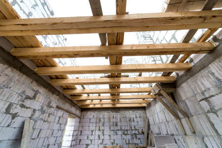 House room interior under construction and renovation. Energy saving walls of hollow foam insulation blocks, wooden ceiling beams and roof frame.の写真素材