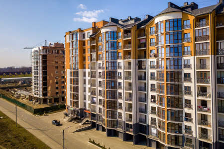 New tall apartment buildings and parked cars and suburb houses on blue sky copy space background.